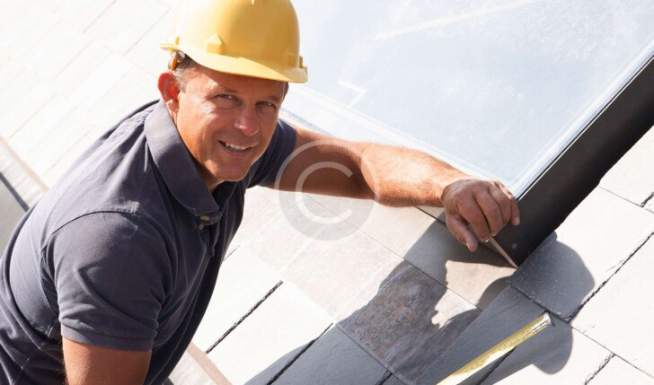 Man on roof with measuring tools